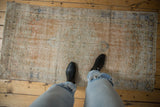 Vintage distressed Oushak runner featuring subdued apricot, ivory, and slate blue motifs.