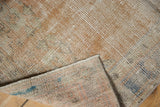 Distressed Oushak rug's worn pile, exposed foundation, and selvage with apricot, ivory, blue colors.