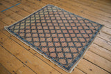Distressed Oushak rug corner with low pile, cobalt blue serpent border, and muted floral pattern.