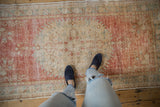 Distressed Oushak runner's faded cherry red field and ivory motifs, showing mostly even wear.