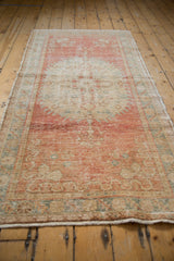 Distressed Oushak rug pile texture with faded cherry red, blush, and ivory hues.