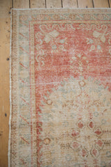 Distressed Oushak runner corner with faded cherry red, blush, ivory, and exposed knot heads.