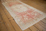 Vintage distressed Oushak runner's textured pile and side selvage in faded red and ivory.