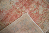 Folded distressed Oushak runner displaying worn cherry red pile, foundation showing through, and hand-knotted reverse.