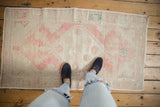 Distressed Oushak runner with faded pink and ivory tones, highlighting worn floral design from above.