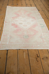 Distressed Oushak runner corner displaying soft pink, ivory, faded teal, and worn pile.
