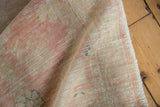 Distressed vintage Oushak rug pile showing beige, dusty blush, and faded teal colors.