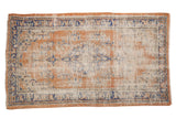 Vintage distressed Oushak rug in apricot, faded royal blue, and ivory floral bouquets.