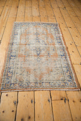 Distressed Oushak rug pile revealing wear to foundation, featuring apricot and faded royal blue.