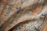 Visible wear on apricot, ivory, and faded royal blue distressed Oushak rug pile.