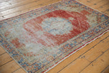 Distressed pile texture showing foundation, faded red, blue, and ivory tones of a vintage Oushak corner.