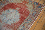 Distressed pile on vintage Oushak rug showing faded red, pale blue, and visible foundation.