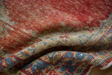 Distressed vintage Oushak rug pile in faded red, beige, and blue with exposed foundation.