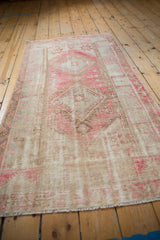 Pink geometric medallion and sand field on a distressed Oushak rug with mostly even wear.