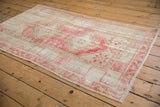 Distressed pink and beige geometric patterns on a vintage Oushak rug corner.