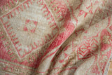Folded vintage Oushak rug with distressed pile, soft pink, and beige geometric motifs.