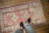 Distressed texture and geometric patterns in pink, ivory, and brown on a vintage Oushak rug.