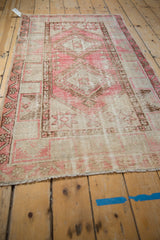 Distressed Oushak rug's geometric double medallion and finned outlines in pink and ivory.