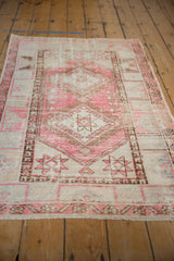 Distressed pink and sand geometric patterns with finned outlines on a vintage Oushak rug.