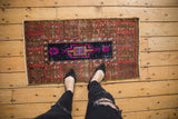Distressed vintage Oushak rug with a navy medallion and fuchsia floral accents, shown for scale.