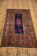 Angled view of a distressed Oushak rug showing the textured wear on its navy and fuchsia medallion.