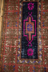 Worn texture of a vintage Oushak rug with fuchsia and violet motifs on a navy ground.