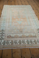 Distressed Oushak rug runner with faded plum, green, and sand floral border motifs.