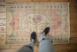 Distressed Oushak rug texture with wear across knot heads, foundation showing through, in rose and ivory.