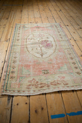 Distressed Oushak rug detail, showing worn rose bouquet medallion and pale blue border with foundation.