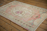 Distressed Oushak rug corner with worn rose field, ivory plant border, and original side selvage.