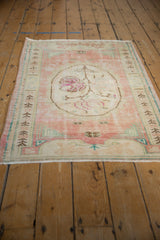 Faded blush and ivory germinating plant border with turquoise accents on distressed vintage Oushak rug.