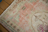 Vintage Oushak rug: distressed rose, ivory, and sand pile with visible foundation and fringe.