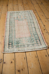 Distressed Oushak rug with peach field, seafoam green border, and even wear revealing foundation.