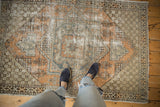 Distressed Vintage Oushak rug's geometric medallion in pale burnt orange and slate blue.