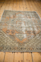Distressed vintage Oushak rug corner, showing worn texture, pale orange and slate blue geometric finials.