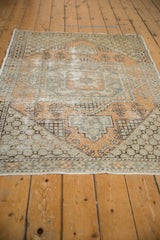 Distressed geometric patterns on vintage Oushak rug, featuring pale orange, slate blue, and beige.