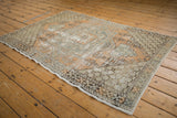 Distressed Oushak rug corner with intact side cord selvage and worn geometric texture.