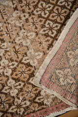 Worn coffee brown floral lattice on distressed Oushak runner, with exposed foundation and intact selvage.