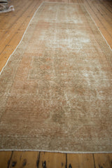 Distressed Oushak runner, its worn pile displaying muted antique ivory and sand tones.