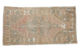 Distressed Oushak rug with faded floral medallion in pale pastel rose and beige.