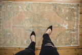 Vintage distressed Oushak rug in pastel ivory and rose with decorative worn texture.
