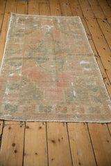 Fringed end of distressed Oushak rug with faded pastels and areas of foundation showing.
