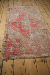 Distressed vintage Oushak rug featuring faded red, silver geometric floral motifs and texture.