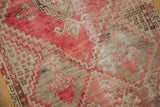 Distressed pile detail of a vintage Oushak rug showing faded reds, pale neutral tones, and geometric floral patterns.
