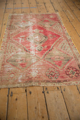 Distressed vintage Oushak rug corner, with faded red, beige, charcoal geometric patterns and visible texture.