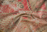 Textured pile with faded red and neutral geometric patterns on a vintage distressed Oushak rug.