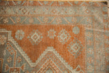 Distressed Oushak runner pile, displaying copper, charcoal, and beige floral motifs.