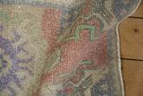 Distressed vintage Oushak rug close-up, showing even wear, geometric patterns, red, green, purple.