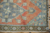 Distressed Oushak rug detail: rust, blue, bronze floral motifs and intact woven selvage.
