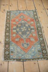 Distressed Oushak rug side, showing rust red field, olive border, and intact selvage.
